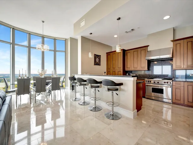 a kitchen with stainless steel appliances kitchen island granite countertop a stove a sink a dining table and chairs