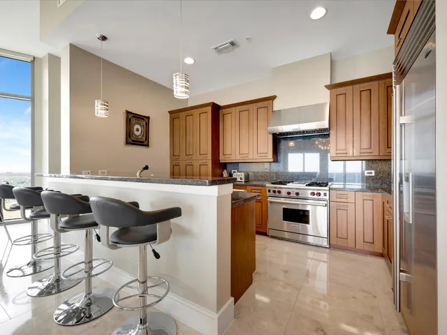 a kitchen with granite countertop a stove a sink and a refrigerator