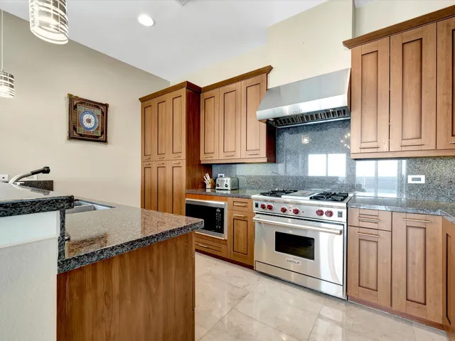 a kitchen with granite countertop a stove top oven sink and cabinets