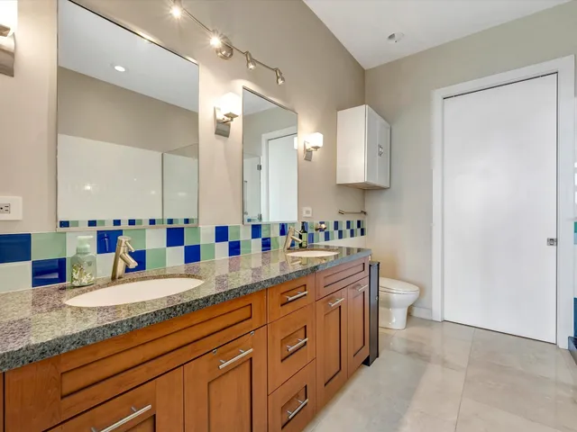 a bathroom with a granite countertop sink mirror and toilet