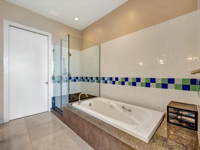 a bathroom with a tub a mirror and a shower
