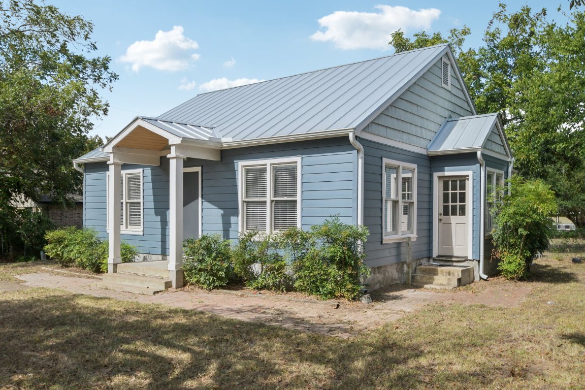 Bungalow featuring a front yard, a standing seam roof, and a metal roof
