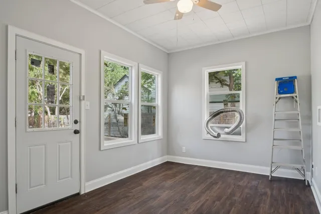 an empty room with wooden floor and windows
