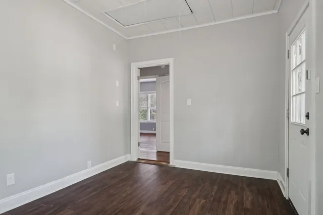 a view of an empty room with wooden floor and a window