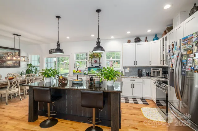 a kitchen with stainless steel appliances kitchen island granite countertop a table chairs and a view of living room
