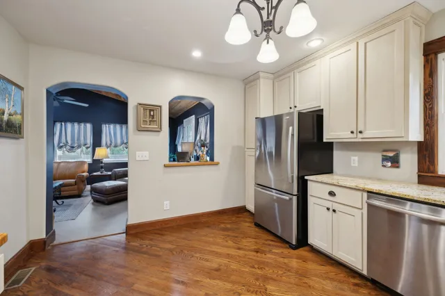 a kitchen with stainless steel appliances granite countertop a stove top oven a sink dishwasher and a refrigerator with wooden floor