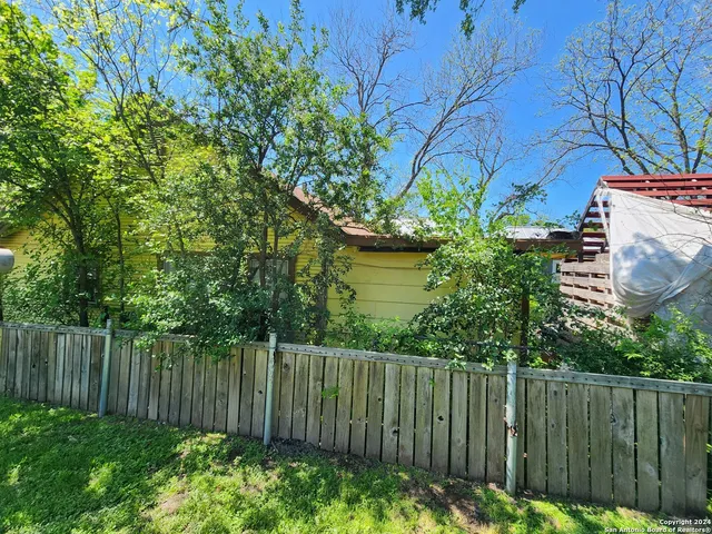 a view of a backyard with plants and wooden fence