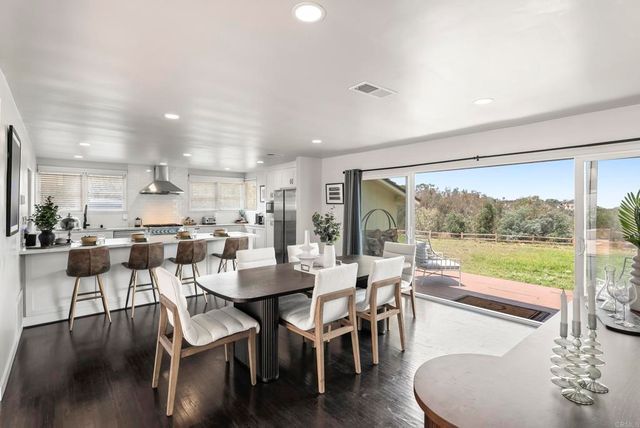 a dining room with furniture and wooden floor to ceiling windows