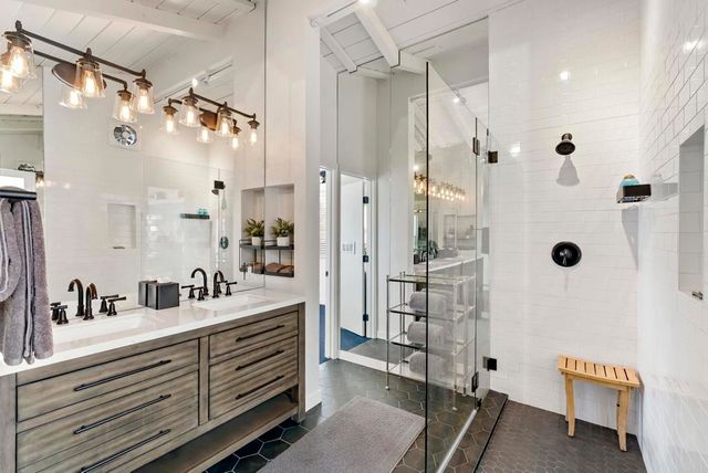 a bathroom with a double vanity sink a mirror a glass door a shower and vanity