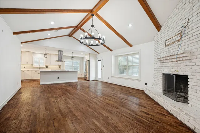 a view of a livingroom with wooden floor and a kitchen