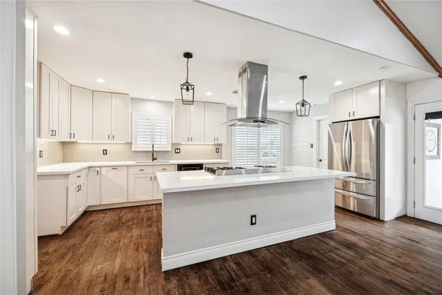 a kitchen with stainless steel appliances sink stove refrigerator and white cabinets with wooden floor