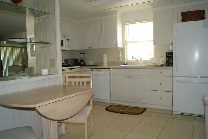 6948 Southeast Delegate Street Hobe Sound, FL 33455 - Photo 13 of 17 a kitchen with granite countertop a sink a stove and cabinets