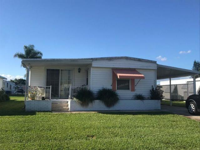 6948 Southeast Delegate Street Hobe Sound, FL 33455 - Photo 2 of 17 a front view of a house with garden