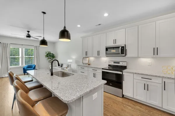 a kitchen with granite countertop white cabinets and stainless steel appliances
