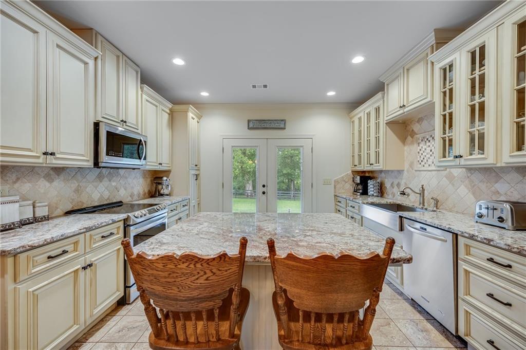 5911 Bent Tree Way Clermont, GA 30527 - Photo 35 of 56 a kitchen with stainless steel appliances granite countertop a stove a sink a microwave a dining table and chairs