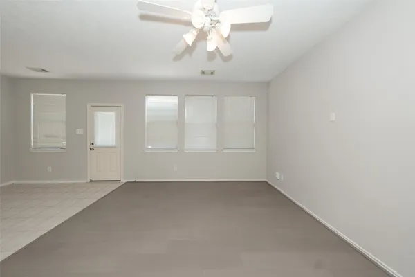 an empty room with chandelier fan and windows