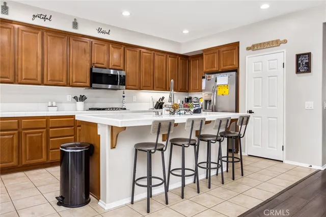 a kitchen with stainless steel appliances granite countertop a table chairs and a refrigerator