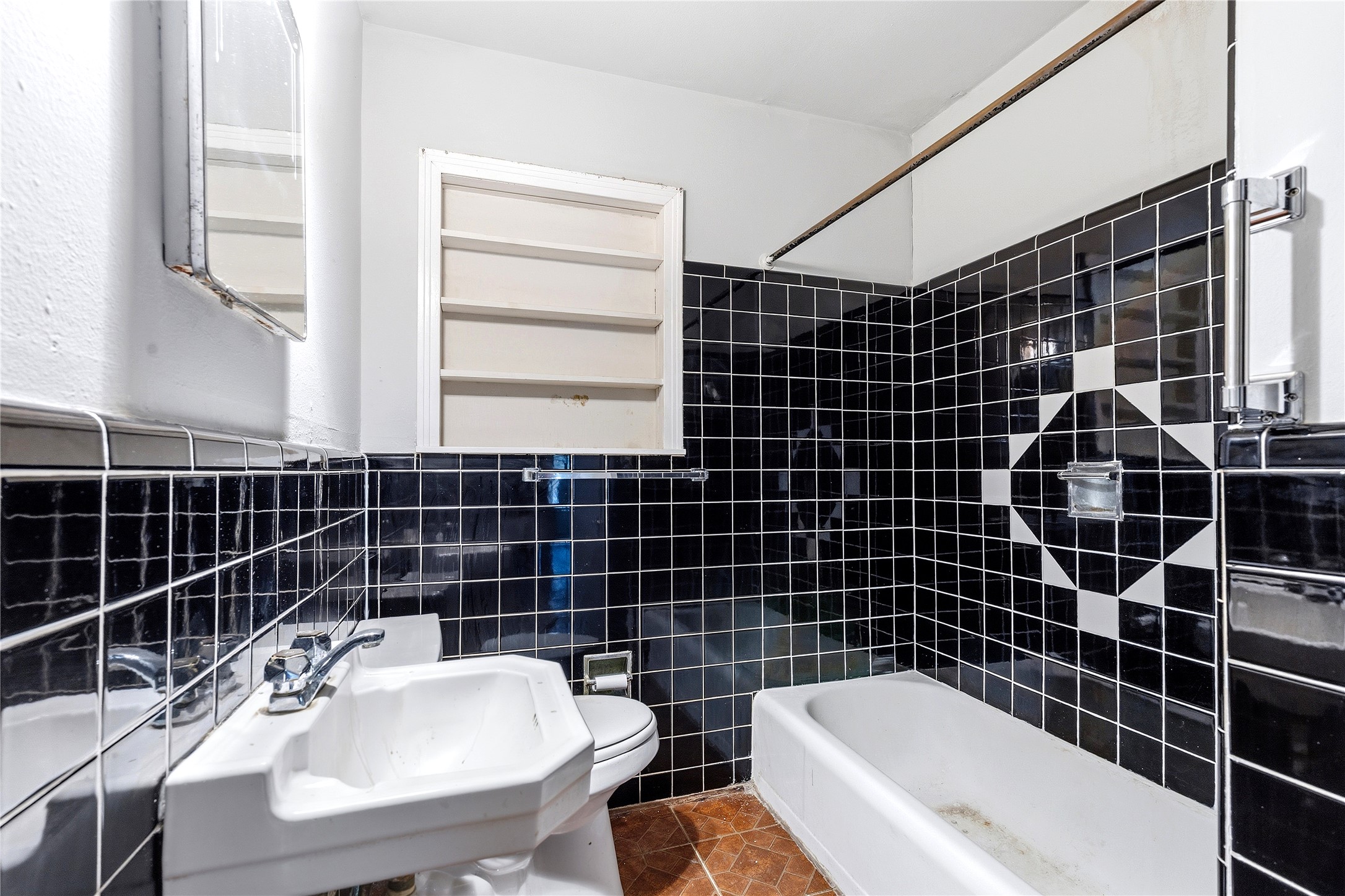 4900 Duval Street Austin, TX 78751 - Photo 20 of 25 Full bath featuring original 1950s black tile, vintage wall-mounted sink, tub/shower combination, and period tile detailing. A distinctive space with preserved mid-century character and strong restoration potential.