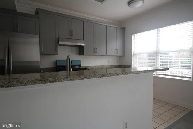 a kitchen with granite countertop a sink window and cabinets