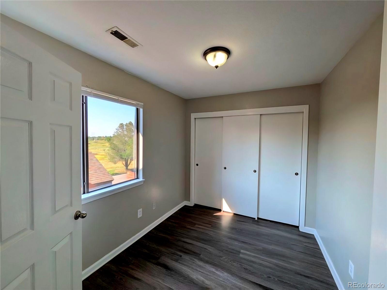 2231 South Buckley Road, Unit 202 Aurora, CO 80013 - Photo 7 of 10 a view of an empty room with wooden floor and a window