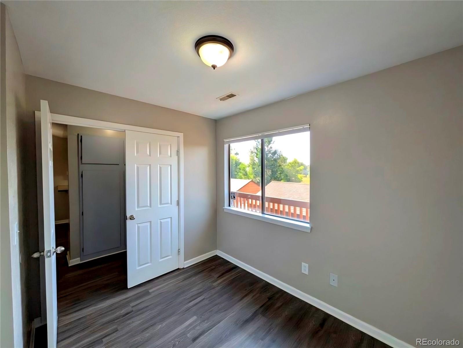 2231 South Buckley Road, Unit 202 Aurora, CO 80013 - Photo 8 of 10 a view of an empty room with wooden floor and a window