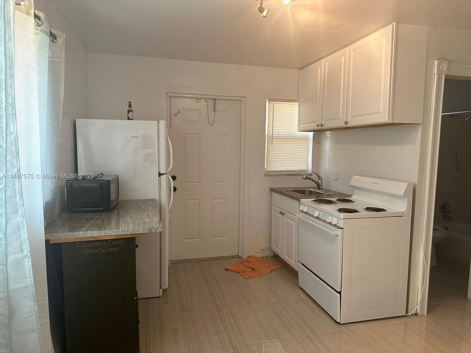 226 Southwest 11th Street, Unit 1 Dania Beach, FL 33004 - Photo 2 of 10 a kitchen with stainless steel appliances white cabinets and a refrigerator