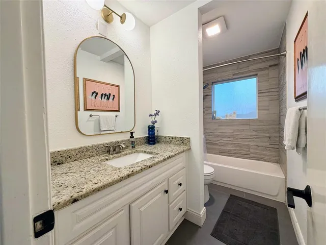 a bathroom with a granite countertop sink toilet and shower