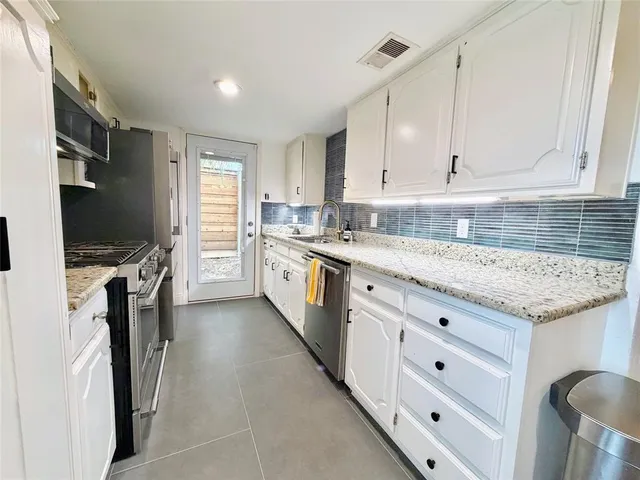a kitchen with granite countertop a sink stainless steel appliances and cabinets