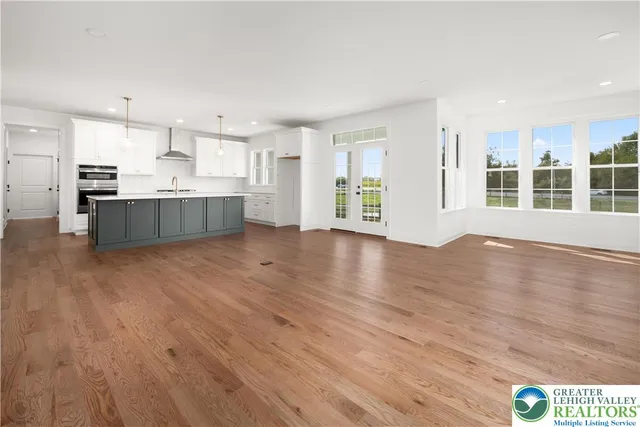 a large living room with wooden floors and kitchen view