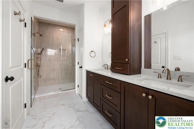 a bath room with a sink double vanity large mirror and a shower