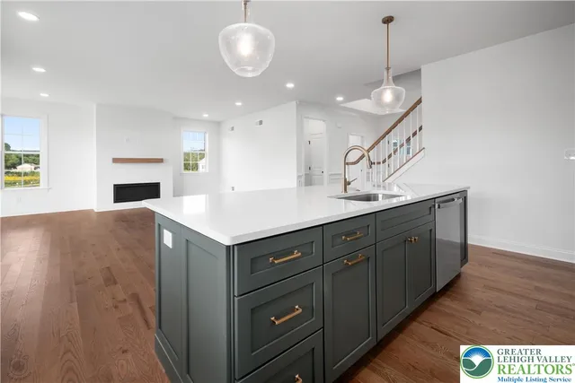 a kitchen with a sink a chandelier stainless steel appliances and cabinets