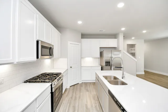 a kitchen with a sink a stove and white cabinets