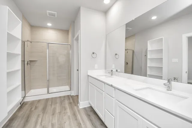a bathroom with a double vanity sink mirror and shower