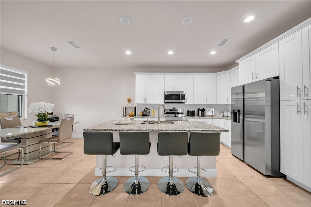 384 Neighborly Road LaBelle, FL 33935 - Photo 15 of 45 a kitchen with stainless steel appliances a dining table chairs refrigerator sink and cabinets