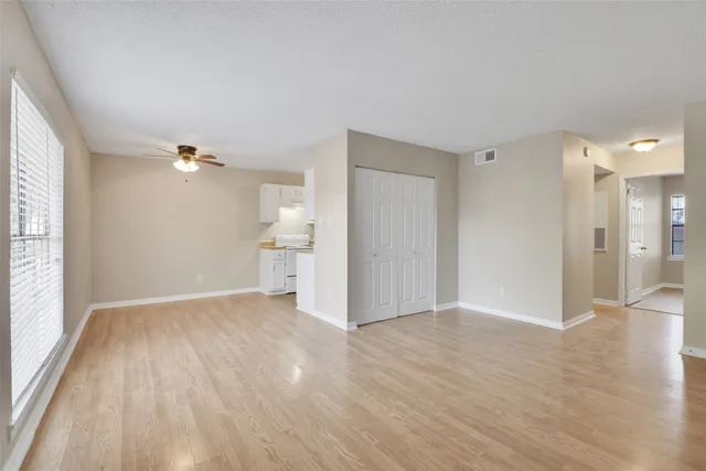 a view of a big room with wooden floor and windows