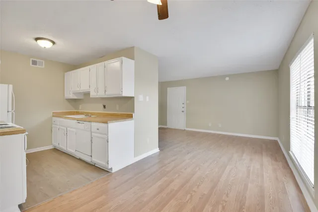 a kitchen with wooden floors and white cabinets