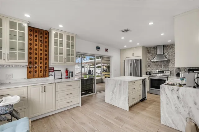 a kitchen with stainless steel appliances kitchen island granite countertop a stove a sink and white cabinets with wooden floor