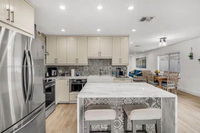 a kitchen with stainless steel appliances granite countertop a refrigerator a stove a sink a dining table and chairs