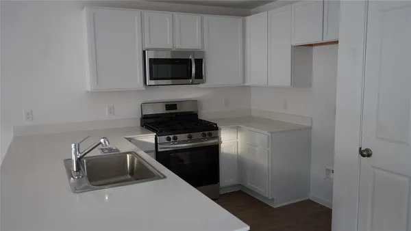 a kitchen with a sink and a stove top oven with wooden floor