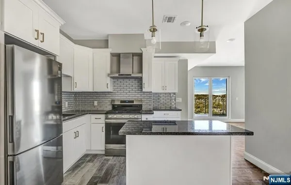 a kitchen with stainless steel appliances granite countertop a refrigerator a stove and a sink