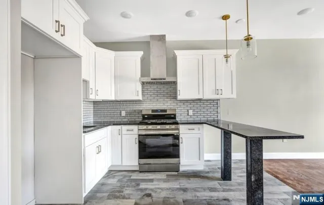a kitchen with stainless steel appliances granite countertop a stove a sink and white cabinets