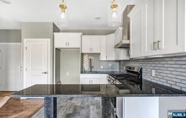 a kitchen with granite countertop a sink a stove and refrigerator