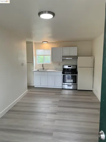 a view of a kitchen with a sink stove cabinets and empty room