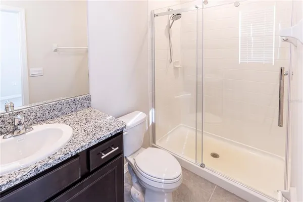 a bathroom with a granite countertop sink a toilet and shower