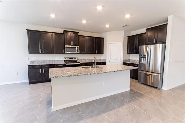 a large kitchen with stainless steel appliances kitchen island granite countertop a large counter top and cabinets