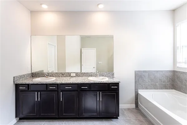 a bathroom with a granite countertop sink a bathtub and a