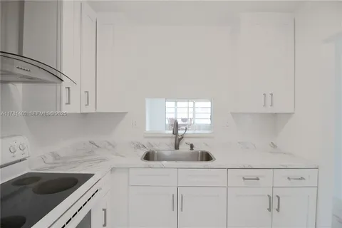 a kitchen with white cabinets a sink and dishwasher