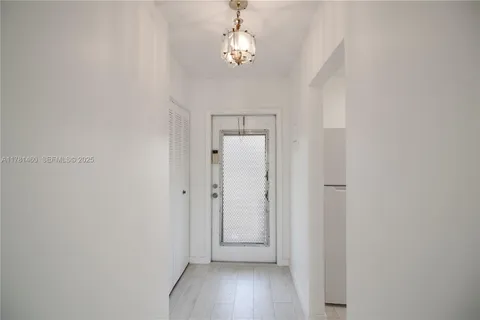 a view of a hallway with wooden floor and a chandelier