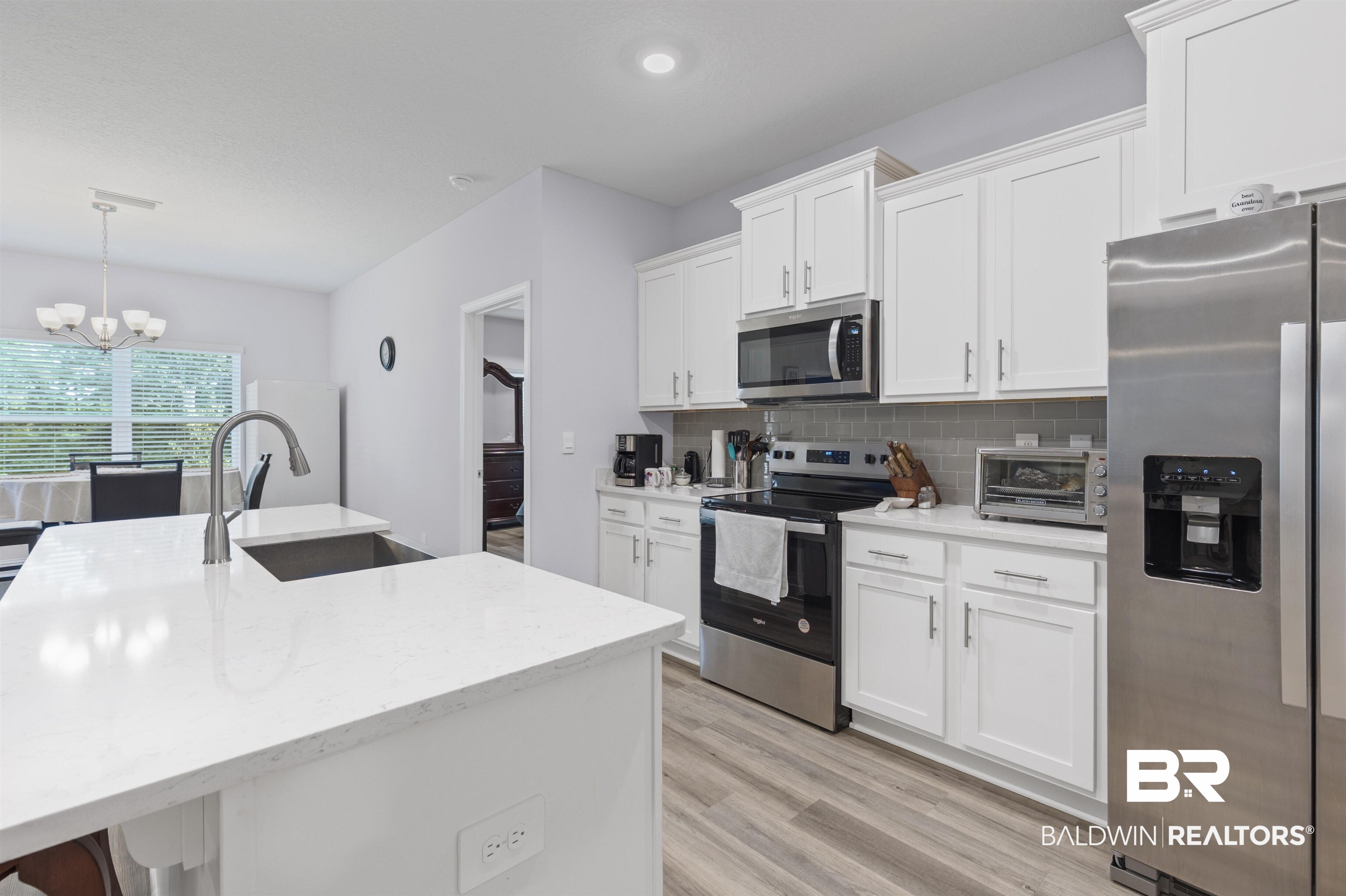 10564 Heirloom Road South Mobile, AL 36608 - Photo 9 of 24 Kitchen with stainless steel appliances, white cabinetry, decorative backsplash, light wood-style floors, and a chandelier