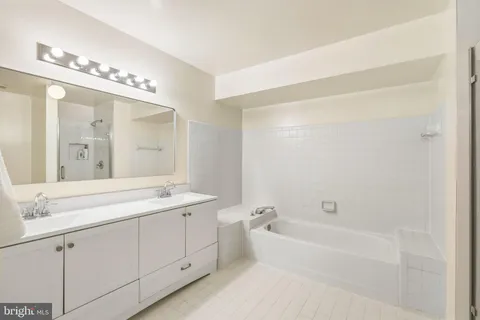 a spacious bathroom with a double vanity sink a mirror and a bathtub